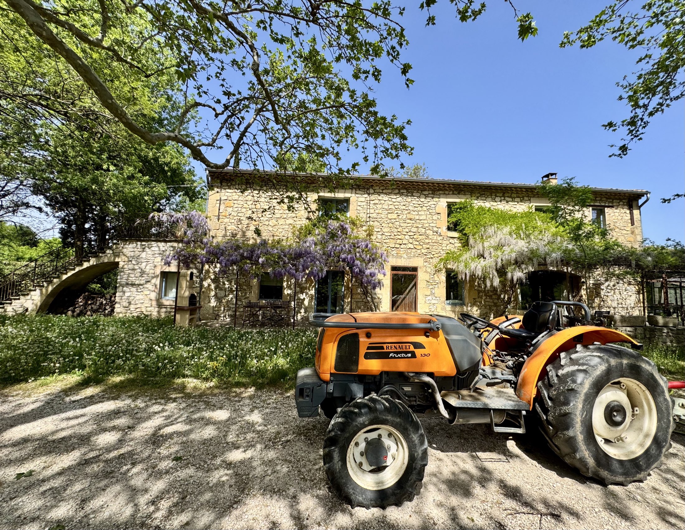 The farmhouse in spring, wisteria in bloom, the farm tractor out front